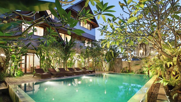A swimming pool with lounge chairs and tropical plants. - Puri Sabina Bed & Breakfast (Jimbaran)
