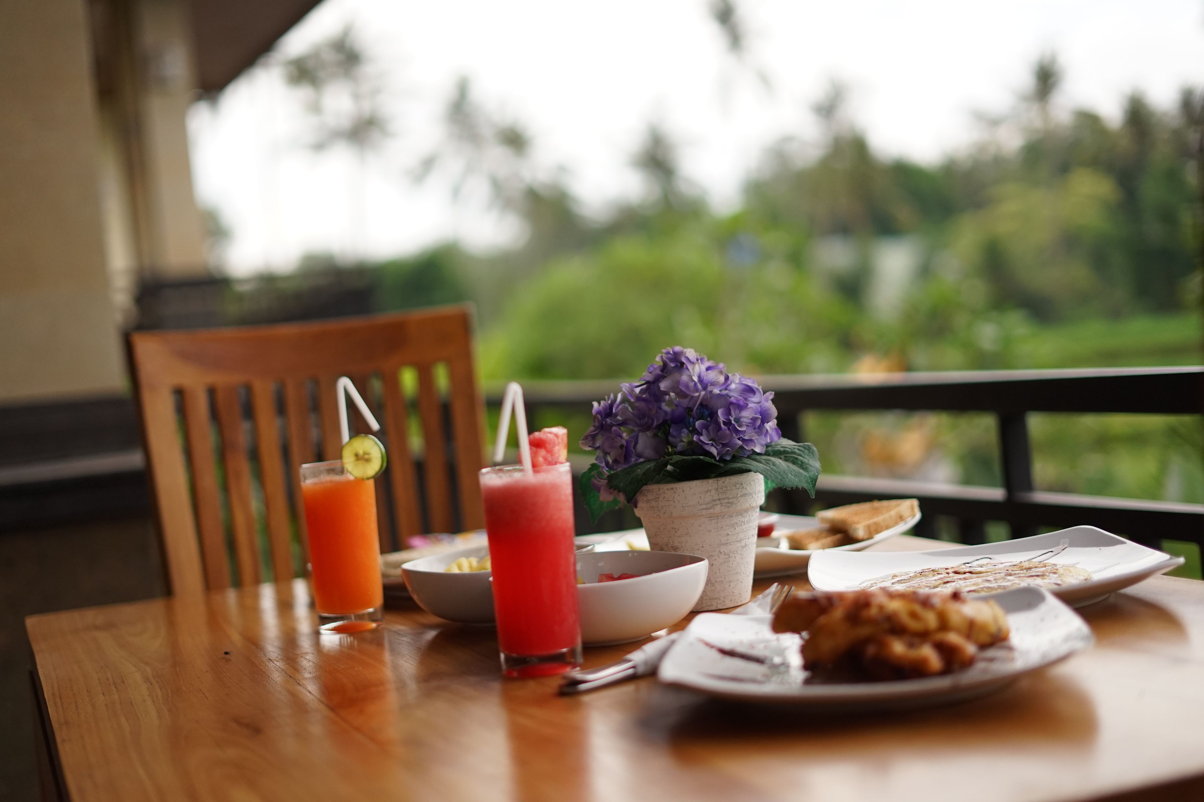A dining table with a drink, a bowl, a plate of food, and a potted plant.