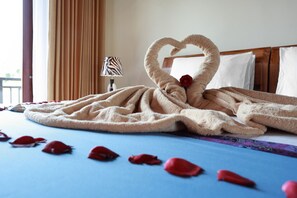 A bed with a heart-shaped towel arrangement and rose petals on a blue bedspread. - Dewi Sri Private Villa (Ubud)