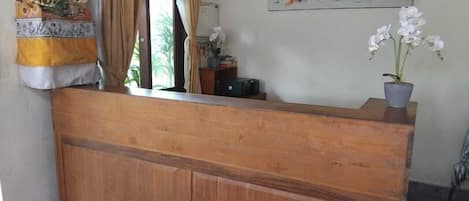 A wooden reception desk with a potted orchid on it.