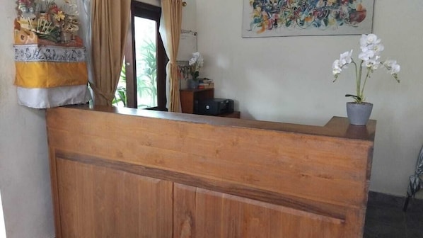 A wooden reception desk with a potted orchid on it. - Dewi Sri Private Villa (Ubud)