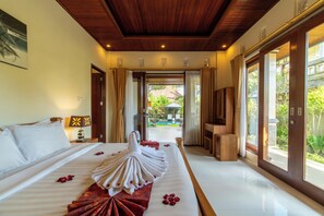 Habitación de hotel con una cama grande, televisión y vista al jardín.