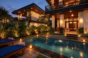 A poolside area with a lounge chair, a small table, and a bench. - Dewi Sri Private Villa (Ubud)