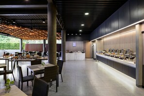 Un comedor moderno con un bufé, mesas, sillas y un mostrador con exhibición de alimentos.