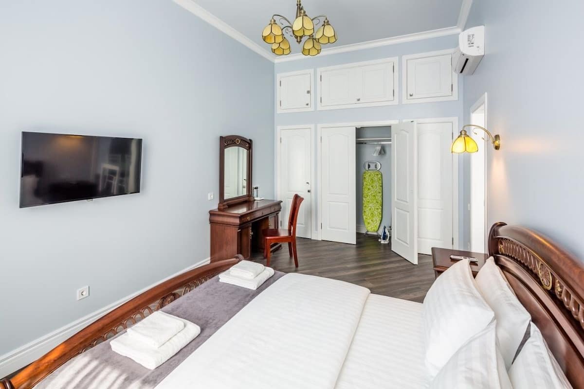 Quarto com cama, escrivaninha, cadeira, televisão e guarda-roupa.