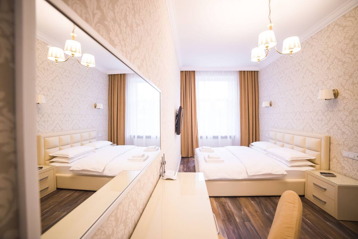 Quarto com espelhos, duas camas, um espelho grande e um candelabro.