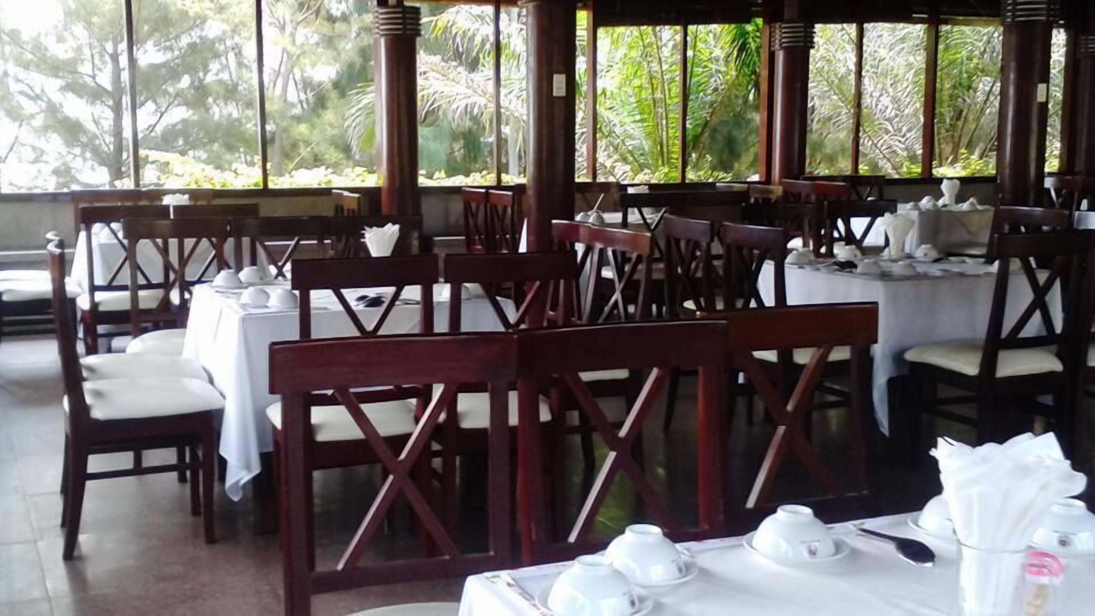 Un restaurante con sillas y mesas de madera, algunas con manteles blancos.
