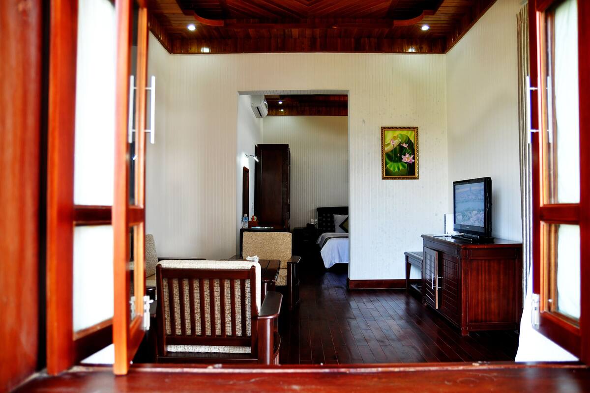Une chambre d’hôtel avec un plancher en bois, un lit, une télévision et un tableau au mur.