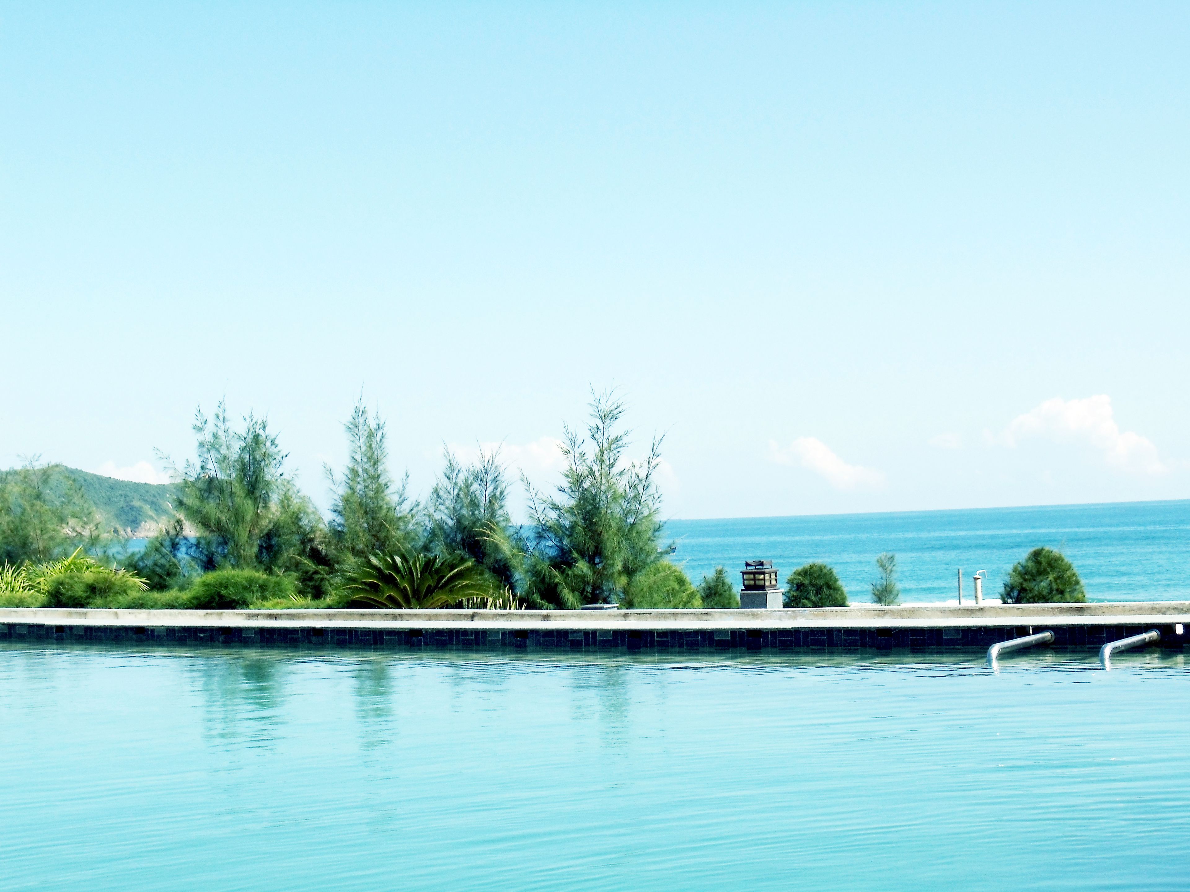 Una piscina con vista sul mare e colline sullo sfondo.