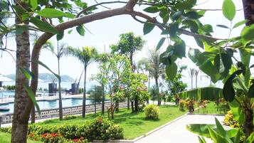 A pool area with a clear view of the water, surrounded by lush greenery and a pathway leading to a building.