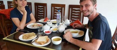 A dining table with plates of food, a teapot, and a water bottle.