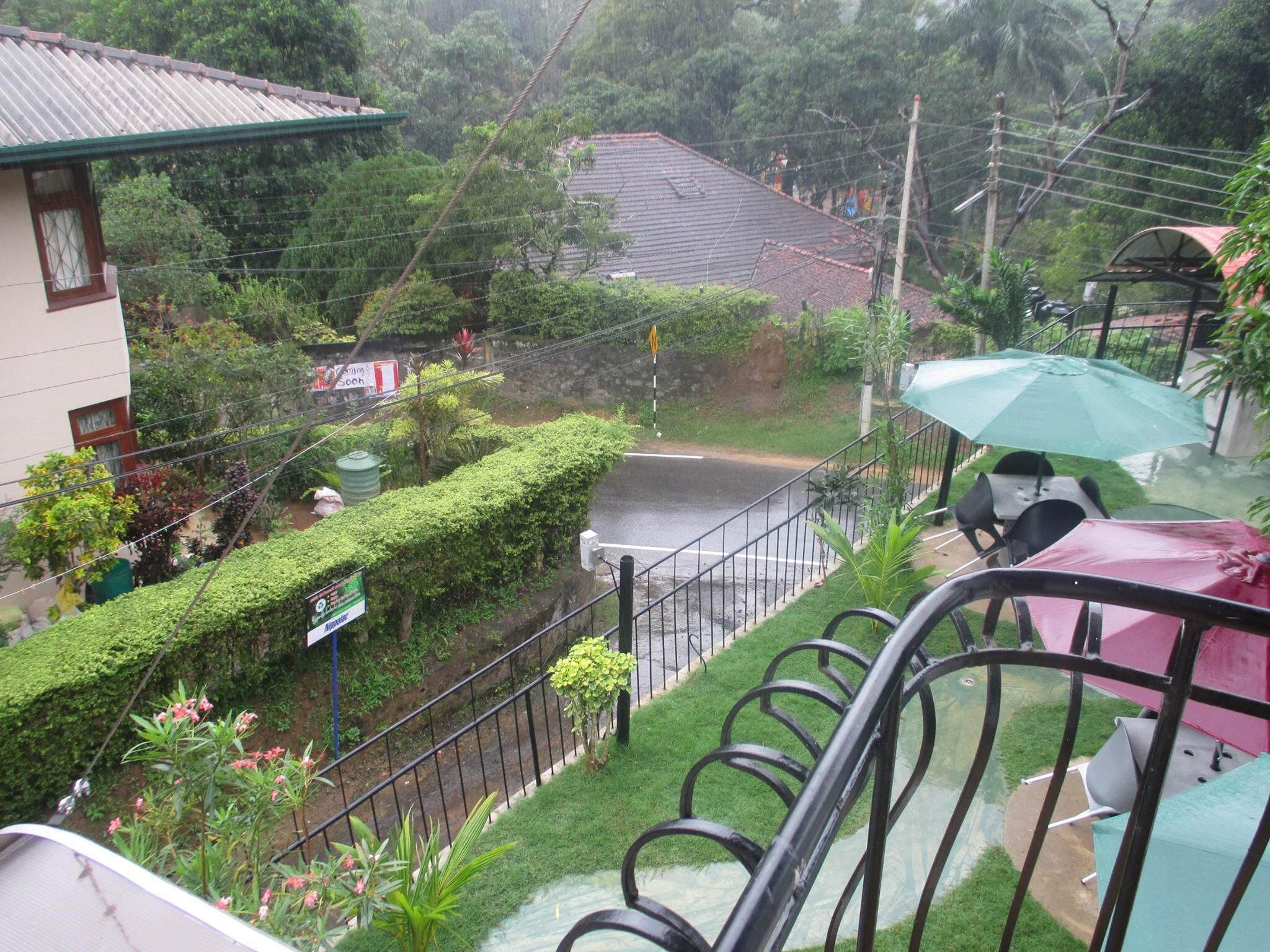 Zona residencial con una calle pavimentada, un paraguas verde y una escalera.