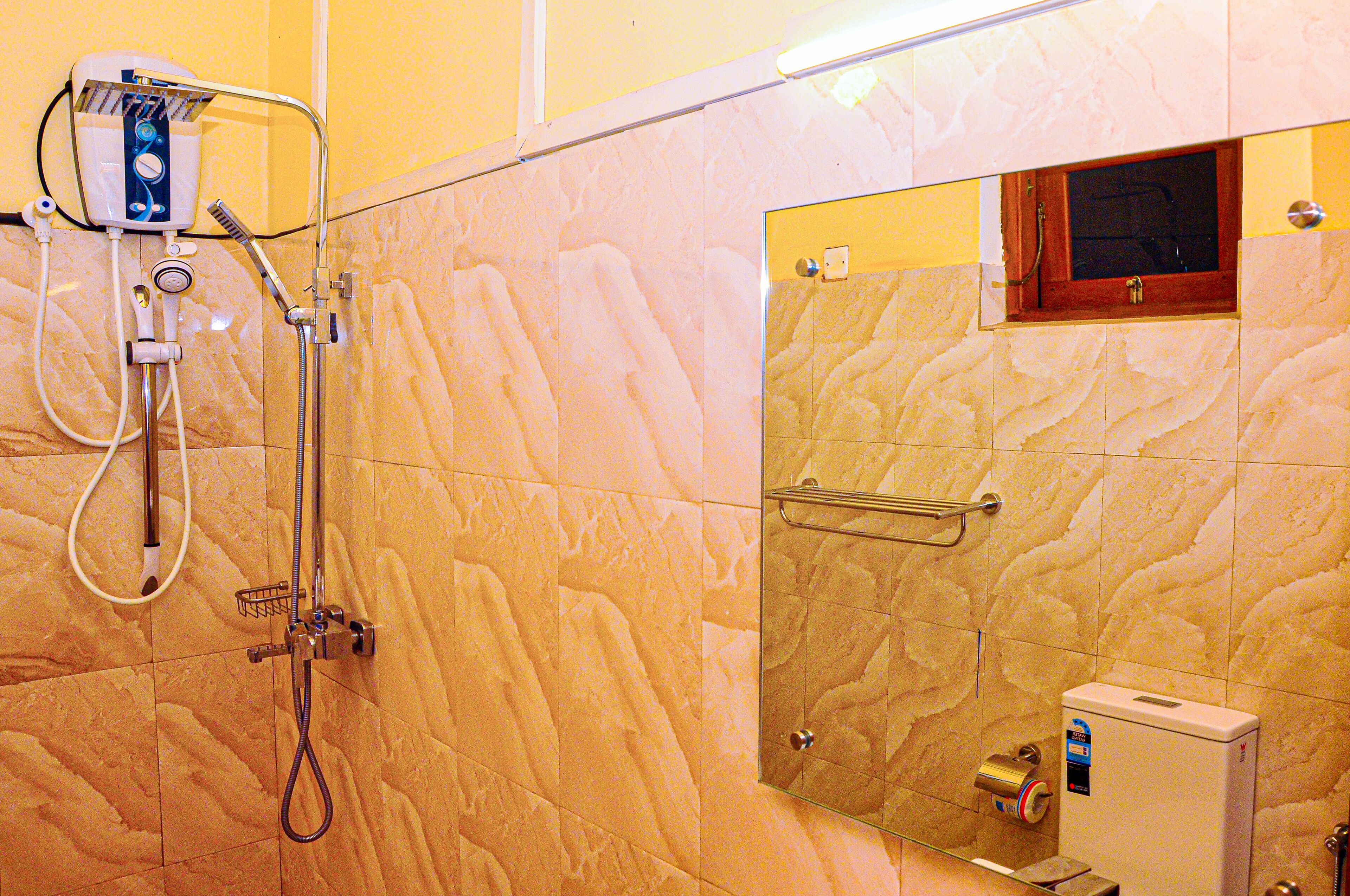 A bathroom with a shower, a toilet, and a glass-enclosed toilet stall.