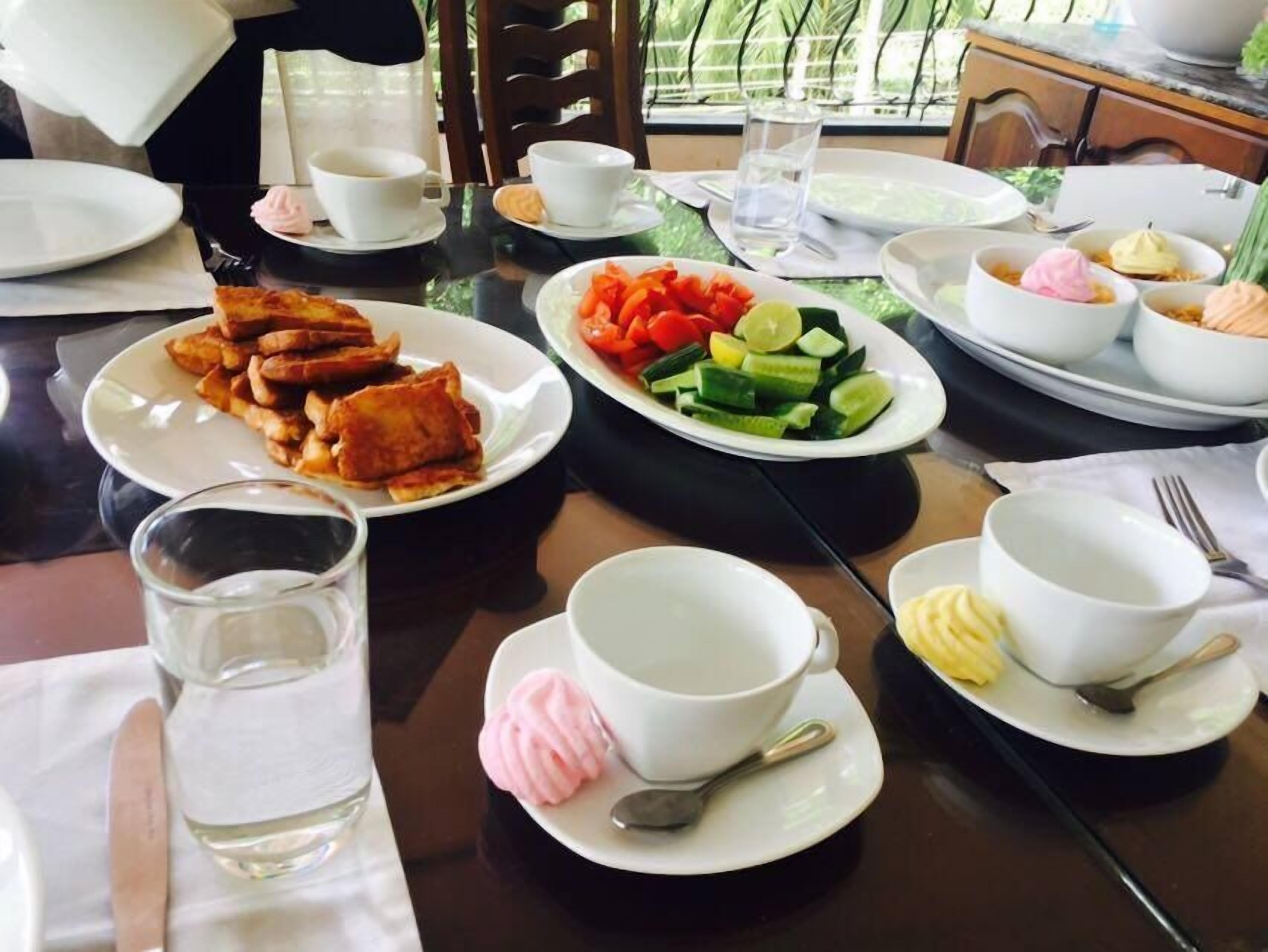 A dining table set with plates of food, bowls, cups, and cutlery, suggesting a meal setting in a restaurant or cafe.