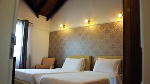 A hotel room with two single beds, a chair, and a patterned wallpaper. - The Planter's Legacy By Fairway (Nuwara Eliya)
