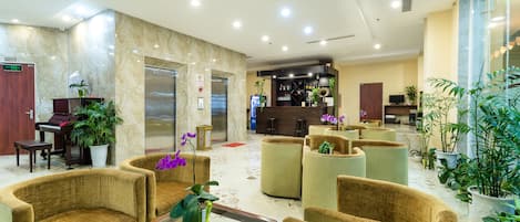 A lobby with seating, a reception desk, a piano, and a bar area.