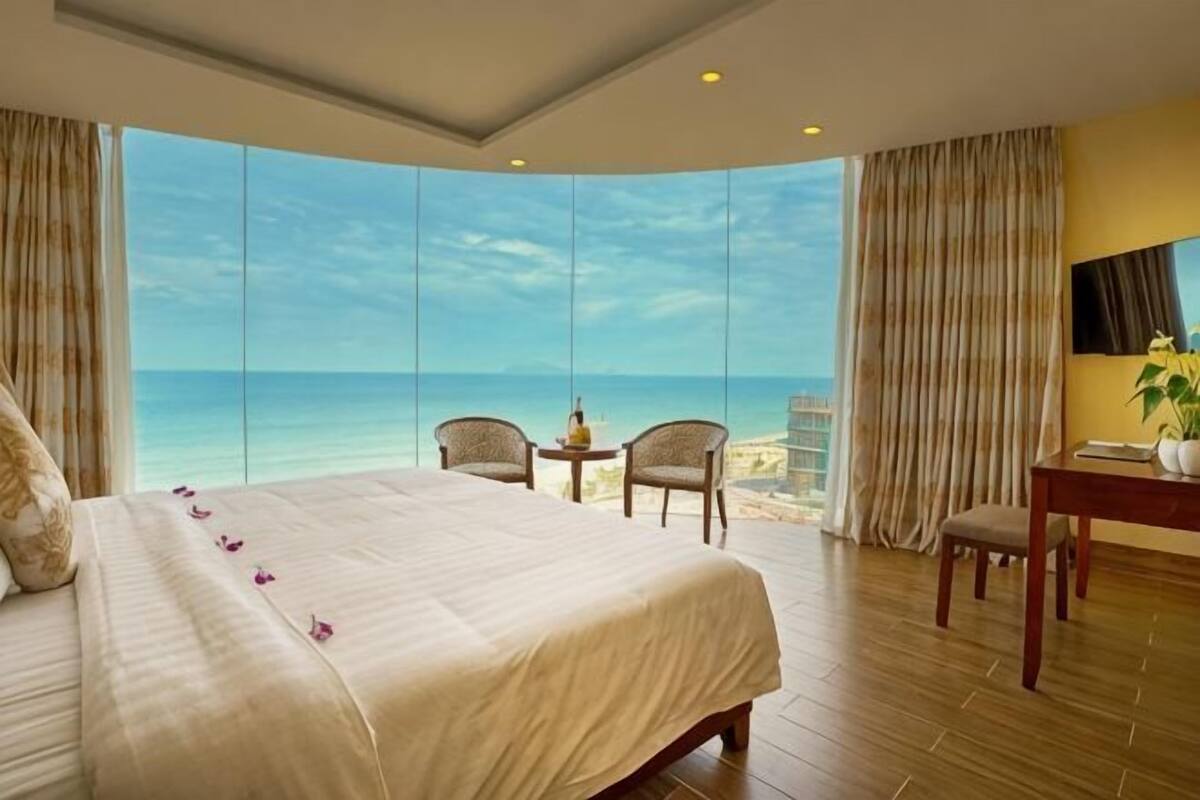 Een hotelkamer met een groot bed, een bureau, twee stoelen en uitzicht op de oceaan.