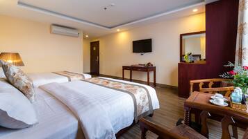 A hotel room with two beds, a desk, a chair, a television, and a mirror.