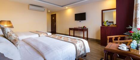 A hotel room with two beds, a desk, a chair, a television, and a mirror.