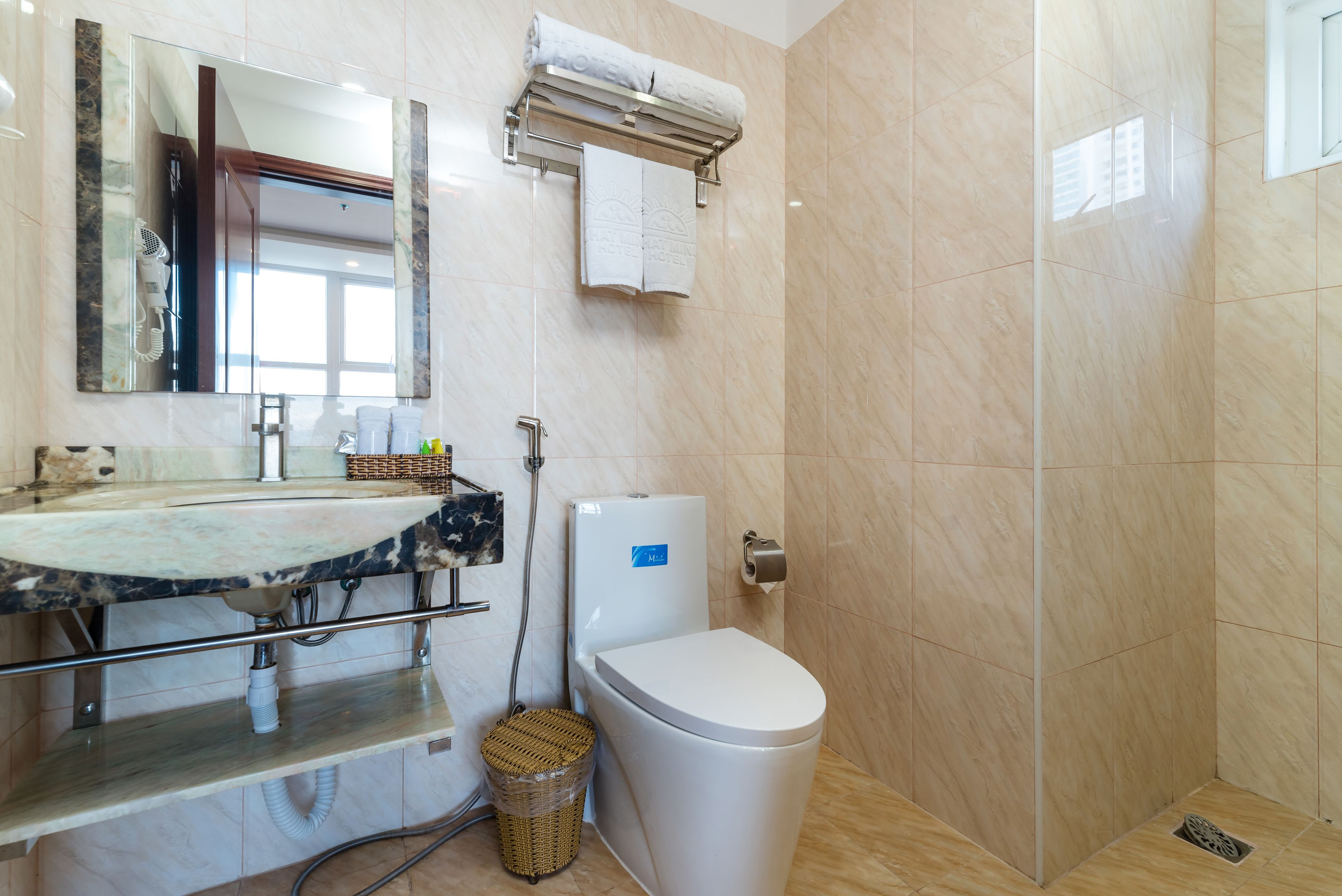 Un baño moderno con lavamanos de mármol, inodoro y zona de ducha.
