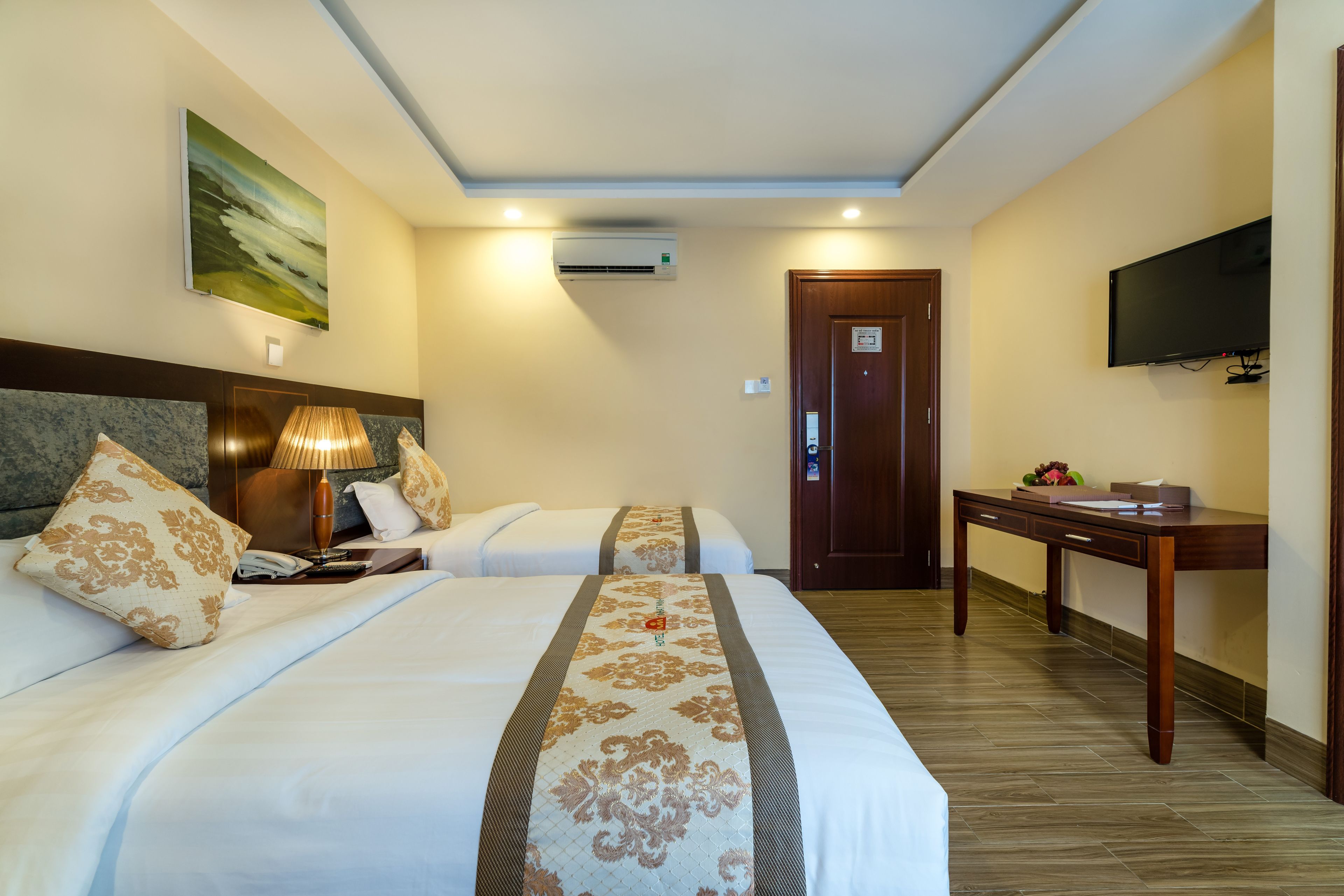 Habitación de hotel con dos camas, un escritorio, un televisor y un aire acondicionado.