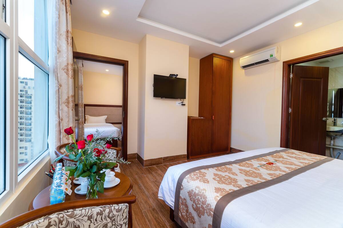 Hotelkamer met een bed, een bureau met een bloevas, een televisie aan de muur en een airconditioning.
