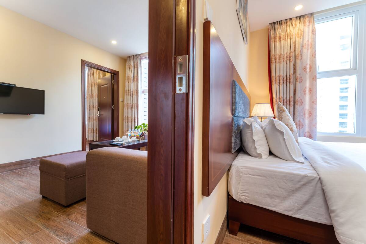 Een hotelkamer met een bed, een zithoek, een flatscreen televisie en een raam met gordijnen.