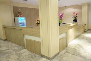 A reception area with a marble floor, wooden reception desk, and a refrigerator with a floral arrangement. - Phet Phangan (Surat Thani)