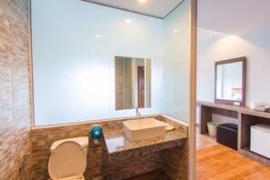 A modern bathroom with a stone wall, a toilet, a sink, and a mirror. - Phet Phangan (Surat Thani)