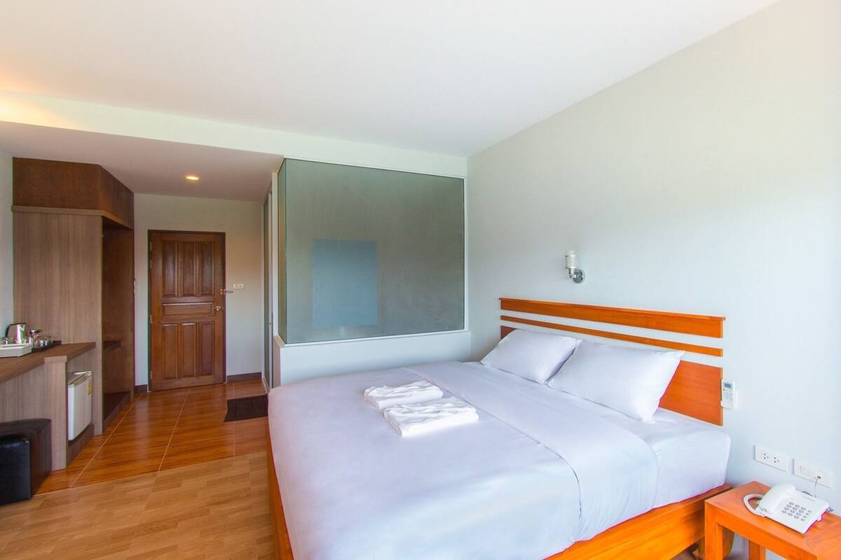 A hotel room with a bed, bedside table, and a large window.