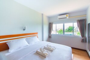 A hotel room with a bed, a window with curtains, an air conditioning unit, and a wall-mounted light. - Phet Phangan (Surat Thani)