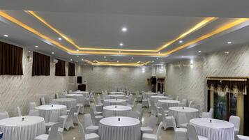 A conference room with round tables and white chairs, marble walls, and recessed lighting.