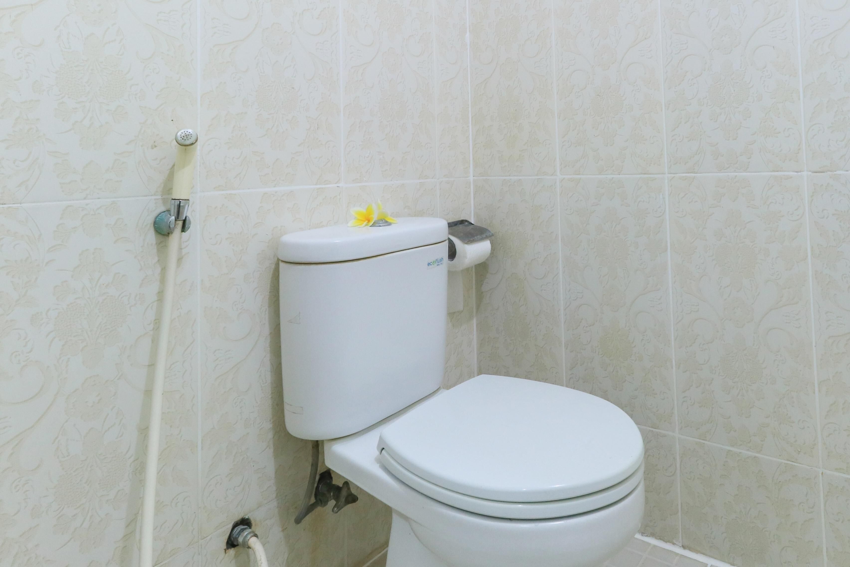 Des toilettes équipées d'un porte-rouleau de papier toilette et d'une poignée de chasse d'eau.