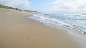 A beach with a sandy shore and waves. - Sugar Beach Resort (Elysium)
