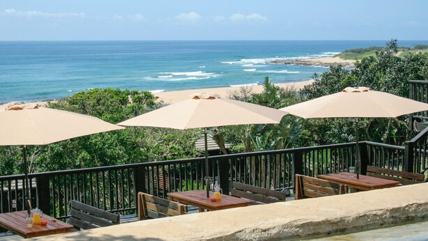 A terrace with outdoor seating, a pool, and a view of the ocean and beach. - Sugar Beach Resort (Elysium)