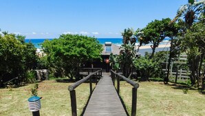 A wooden pathway leading to a building with a view of the ocean. - Sugar Beach Resort (Elysium)