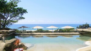 A pool with a view of the ocean, surrounded by rocks and a potted plant. - Sugar Beach Resort (Elysium)