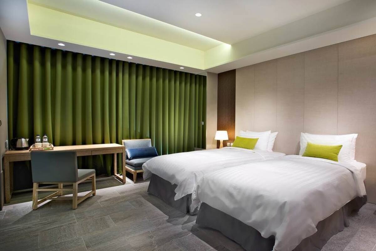 Et moderne hotelværelse med to senge, et skrivebord og en stol.