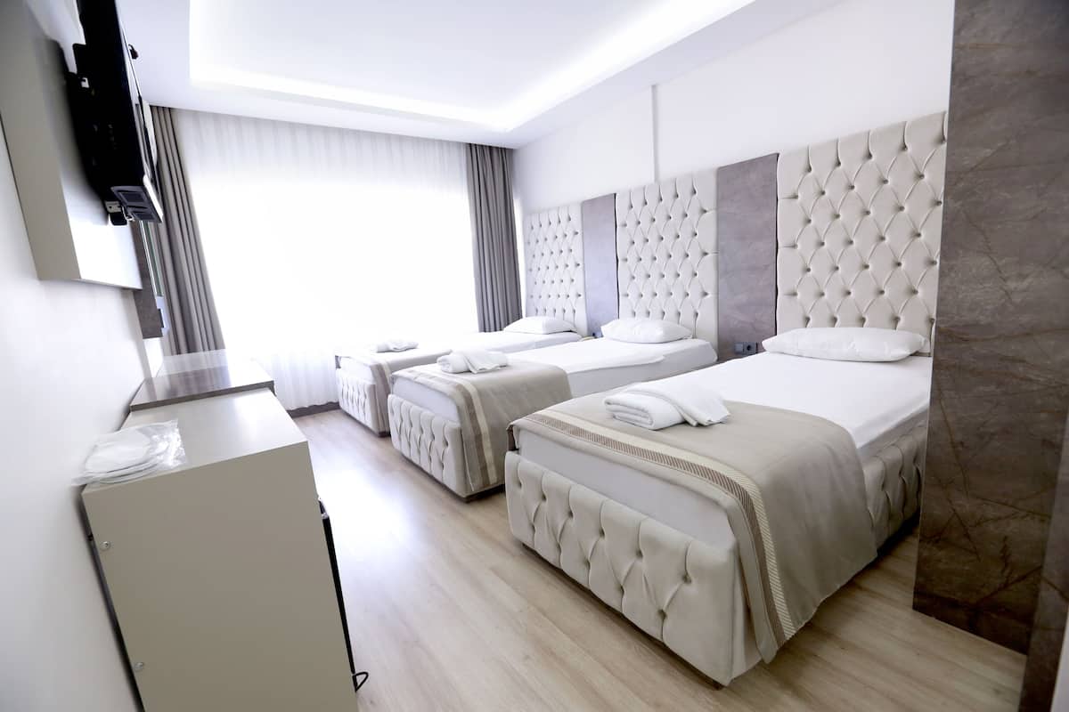 A hotel room with three beds, a flat-screen TV, and a minibar.