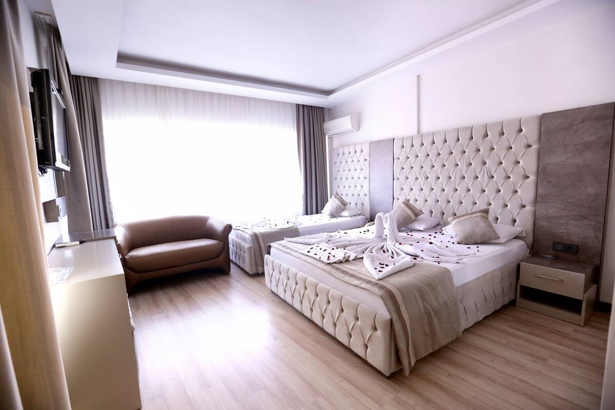 A modern hotel room with a large bed, a sofa, a TV, and a desk.