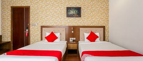 A hotel room with two beds, each with red and white bedding, a wooden headboard, and a geometric patterned wall.