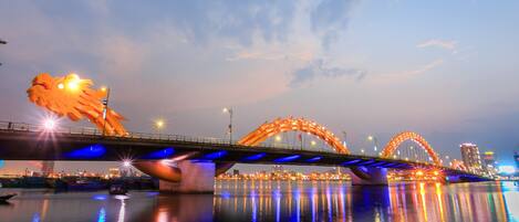 A bridge with illuminated arches and a large sculpture.