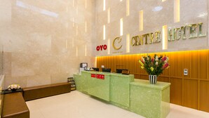 Bancada de recepção de hotel com parede de mármore e uma placa com a inscrição 'CENTRE HOTEL'.