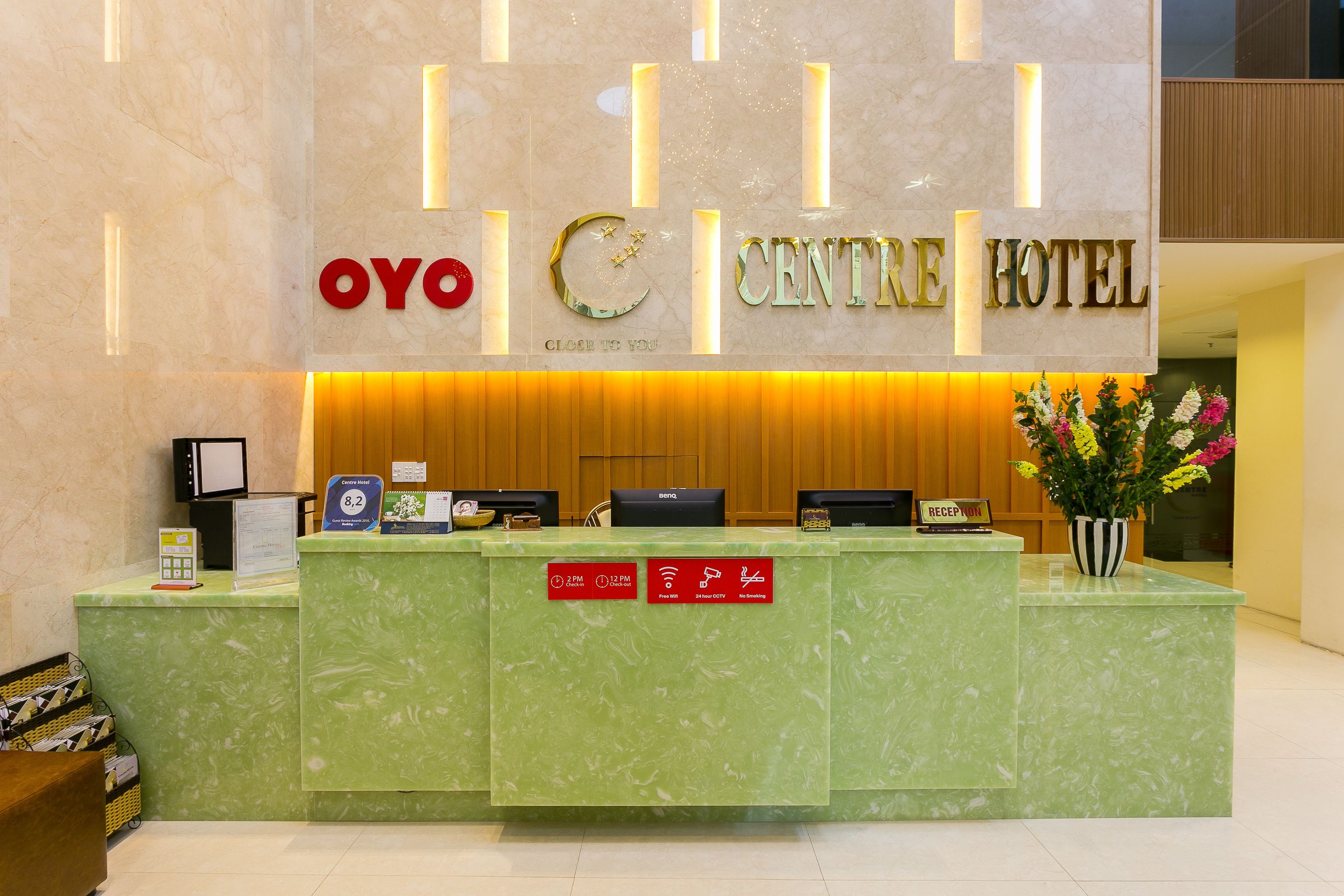 A hotel reception desk with a green marble counter, a reception sign, and a sign indicating Wi-Fi availability.