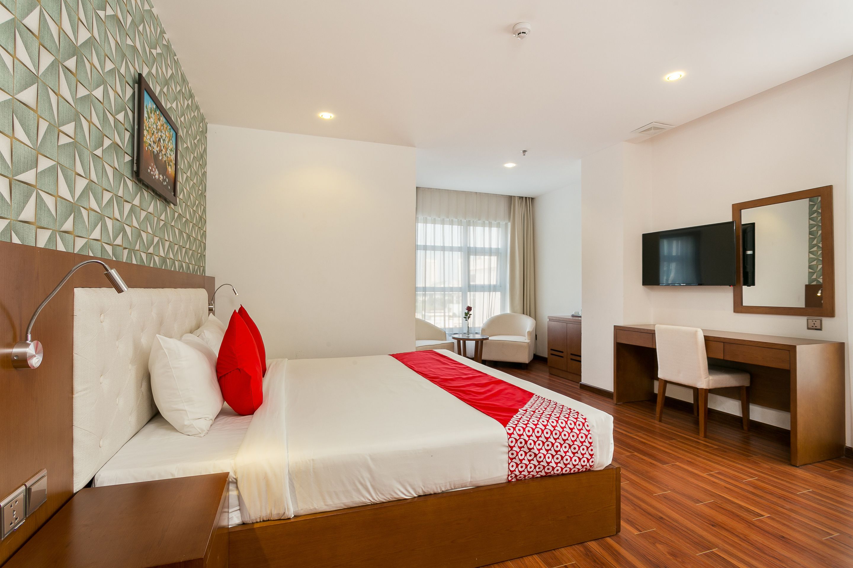 A hotel room with a bed, a desk, a chair, a TV, and a window.
