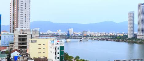 A cityscape with a river, a bridge, and mountains in the background.