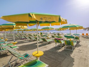 Na praia, espreguiçadeiras, guarda-sóis, toalhas de praia