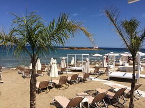Une plage avec des transats, des parasols et une vue sur la mer.