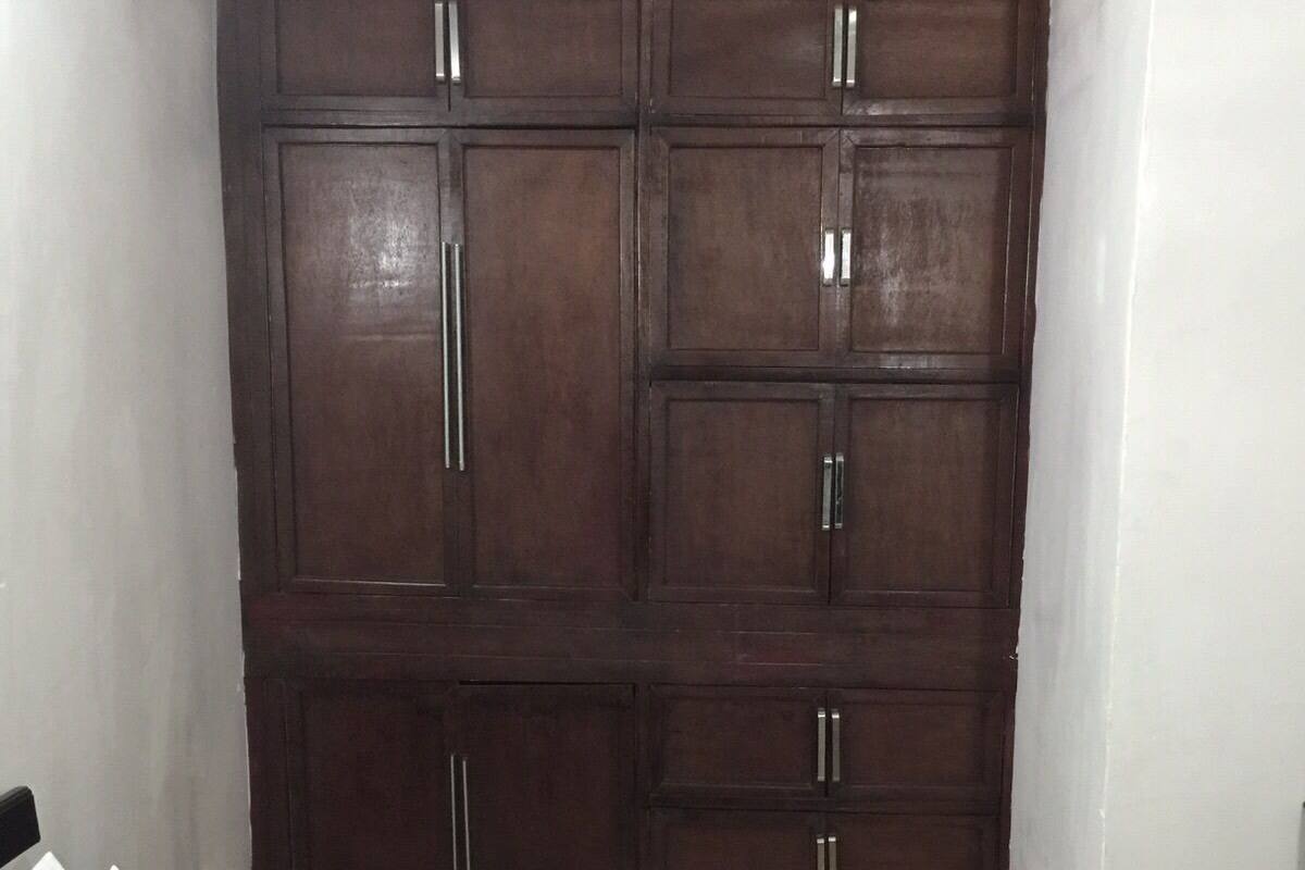 A bedroom with a large wardrobe, a bed, and a nightstand.