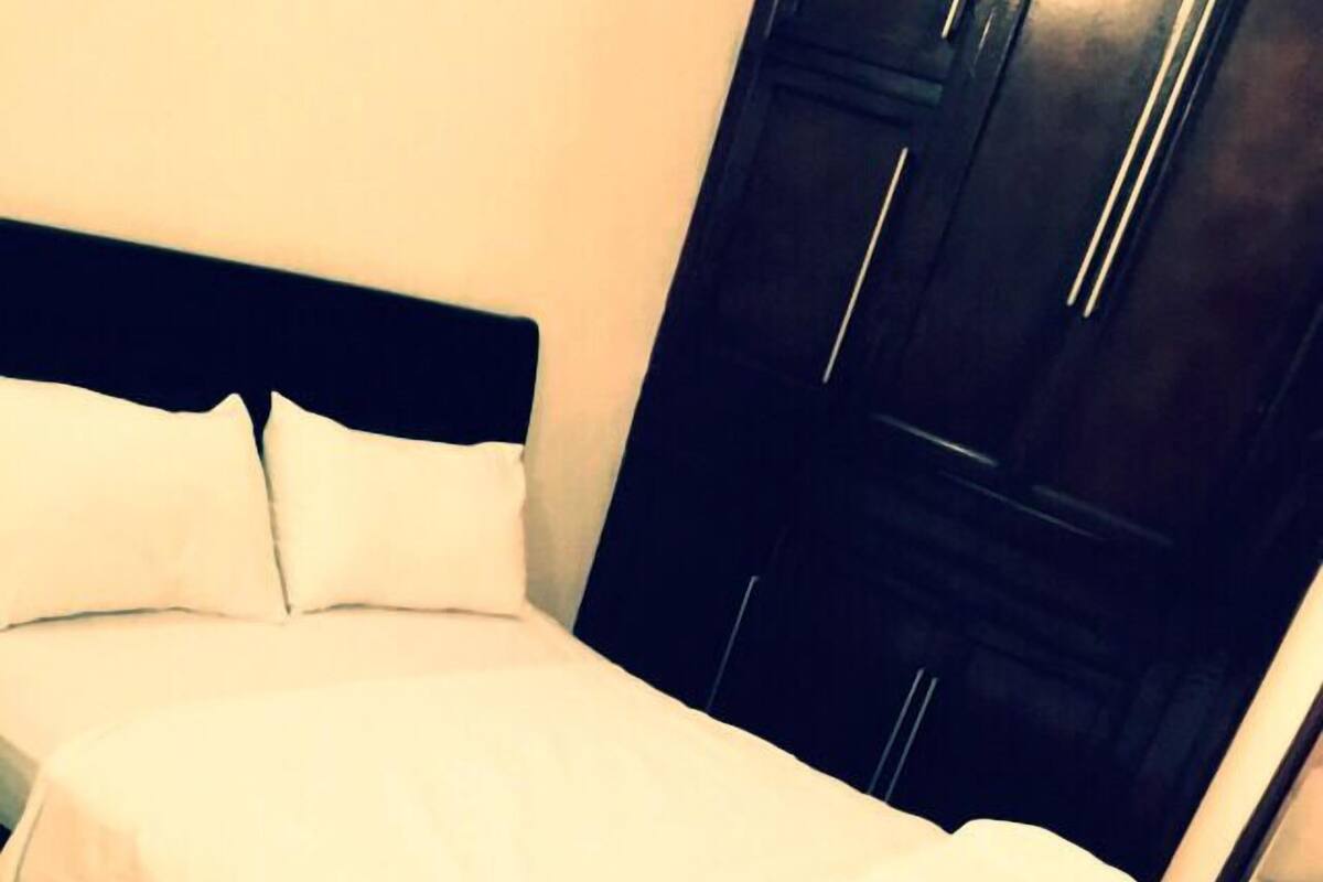 A bed with white bedding in a room with dark wooden furniture.